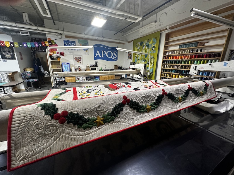 the interior of the quilting studio with apqs machines and quilts